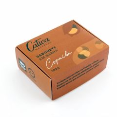 Fundo branco com caixa de papel na cor marrom claro ao centro descrito Cativa Natureza Sabonete em barra copaíba 100g. Enriquecido com Óleo de Copaíba e Óleos essenciais de Lavanda e Melaleuca, proporciona limpeza suave que acalma e purifica a pele.