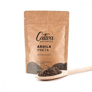 Fundo branco com embalagem de papel marrom ao centro descrito Cativa Natureza argila preta, desintoxicante, rica em silício e titânio, fontes minerais selecionadas 100% naturais do Brasil 100g com uma colher de madeira na lateral esquerda contendo argila